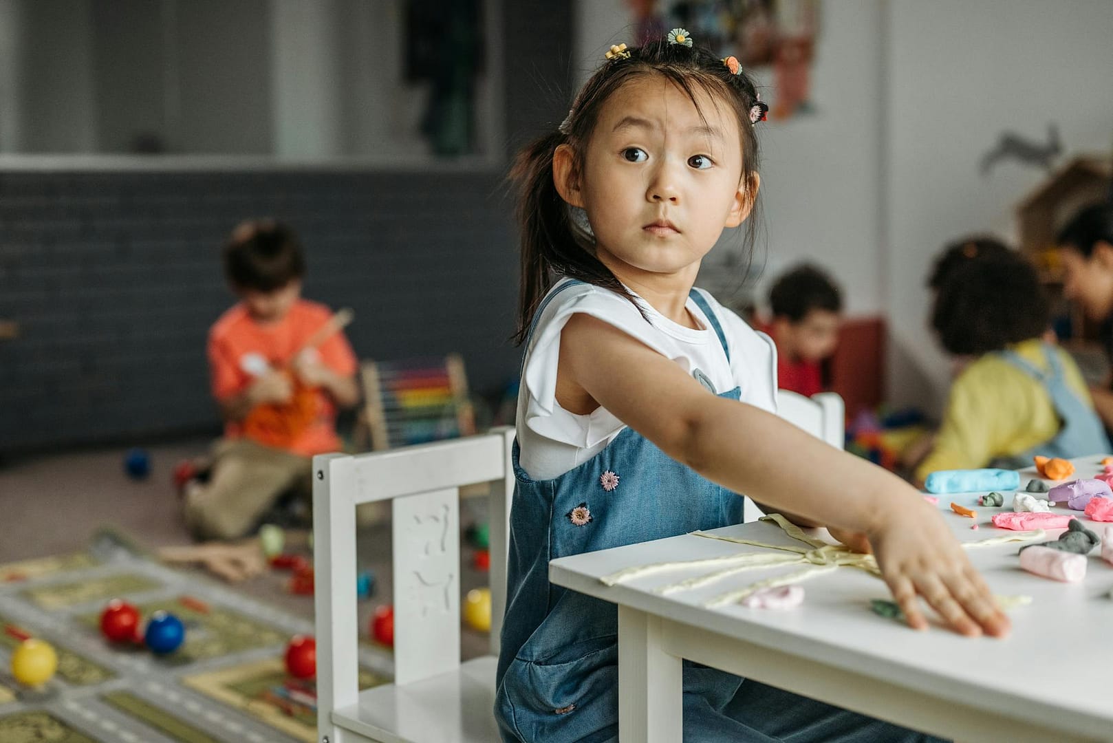 Young girl in classroom exploring creativity with hands-on activities, surrounded by peers.